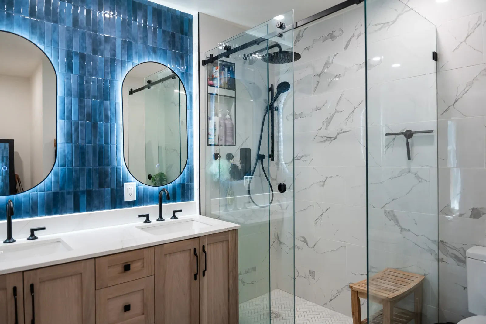 Modern bathroom renovations in Calgary with blue subway tiles, custom vanity and a luxurious matte black shower