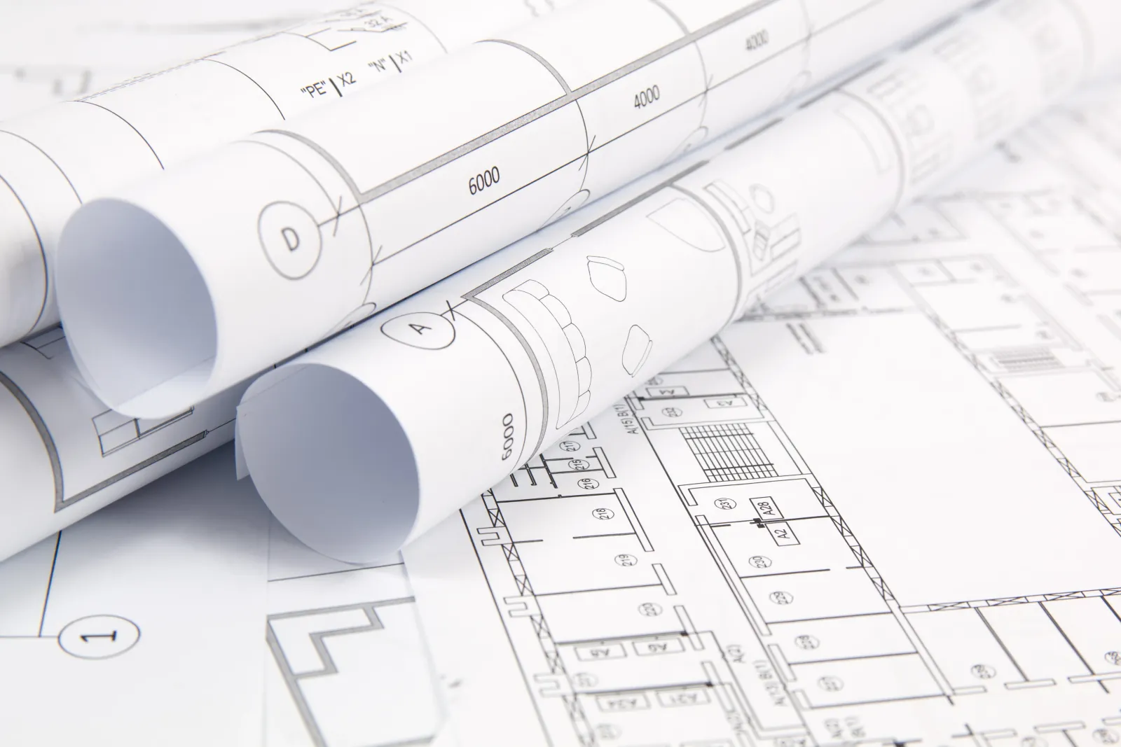 A top-down view of building permits and a secondary suite floor plan on a wooden desk, surrounded by drafting tools like a ruler, pencil, and pen.