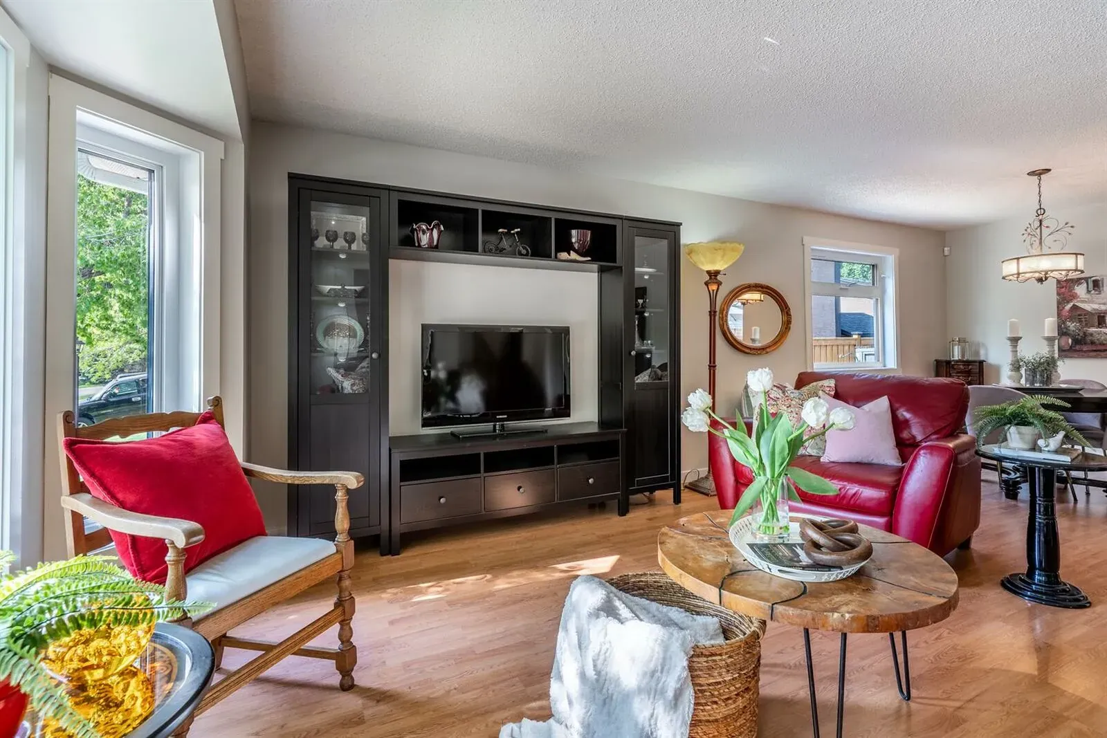 Luxury living room transformation with red leather seats, plants and a black surround fireplace in a Calgary home renovation