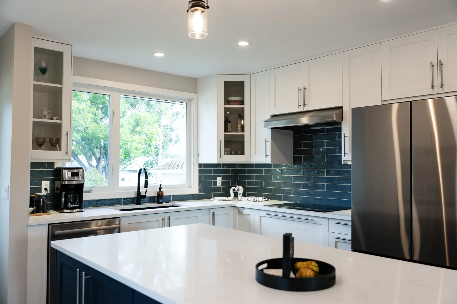 Glossy blue subway tile backsplash reaching ceiling behind hood in Calgary kitchen renovation
