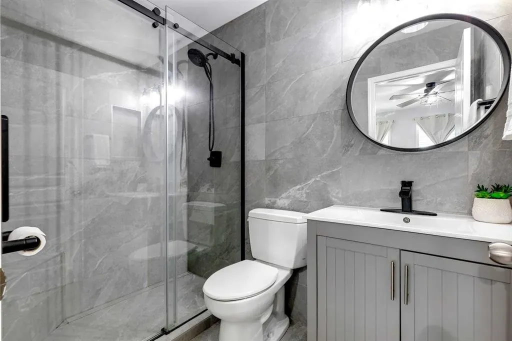 Sleek and modern bathroom renovation in Calgary with grey features and a custom shower with matte back finishes