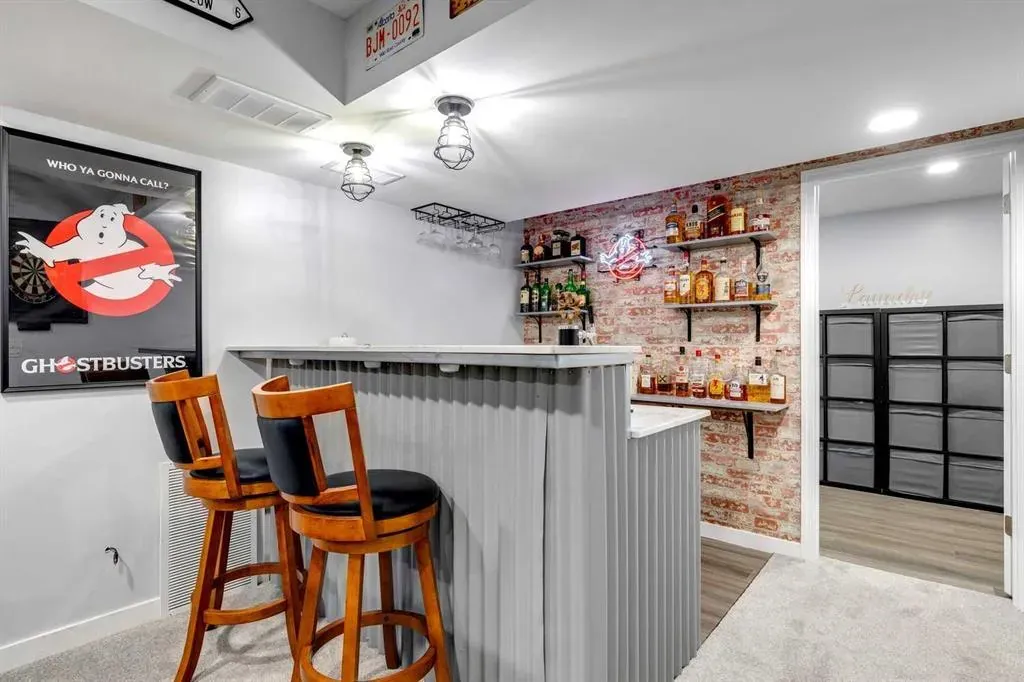 Basement renovation in Calgary with a custom bar with a feature wall and a bar
